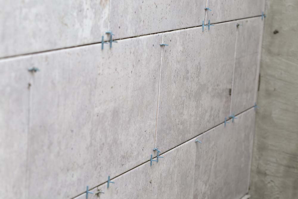 Tiles installation with spacers between ceramic tiles on the wall - renovation stage