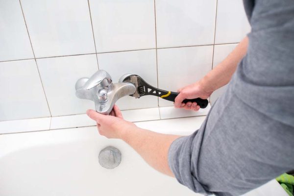 Plumber uninstalling water faucet in the bathroom